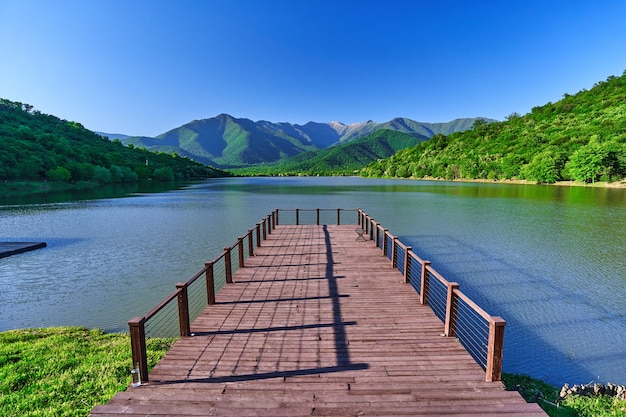 Landscape of wooden pier with beautiful lake and mountains view. Serene quiet peaceful atmosphere in nature