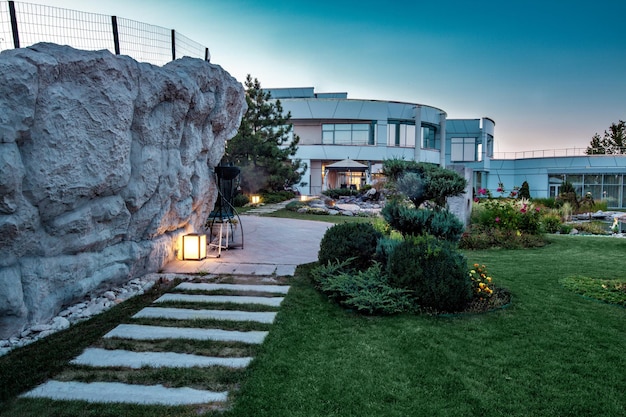 Landscaped backyard of luxury country estate on green lawn in summer twilight