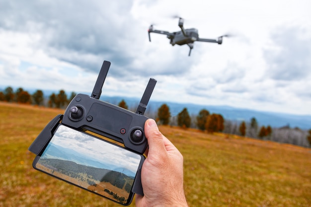 Landscaping on a drone. A young man holds in his hand a quadrocopter control panel with a monitor and an image of mountains