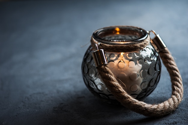 Lantern with a lit candle on concrete table