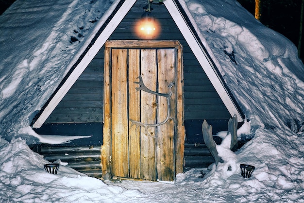 Lappish traditional house at the reindeer farm in winter Rovaniemi, Lapland, Finland. Night snowfall. Toned