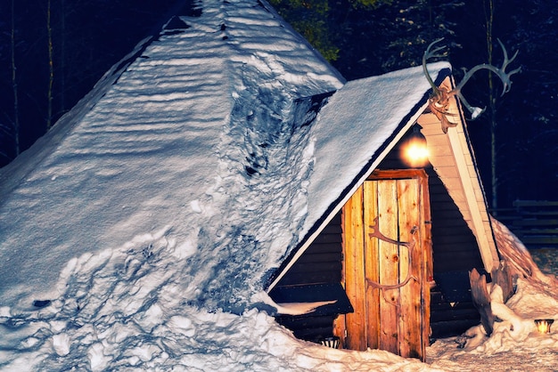 Lappish traditional house of the reindeer farm in winter Rovaniemi, Lapland, Finland. Night snowfall. Toned