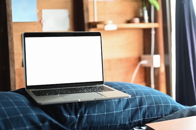 Laptop on the bed in morning time with soft light from window Empty screen for advertise text