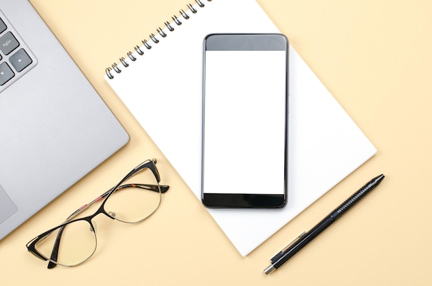 Laptop blank notepad phone and glasses on a yellow background Freelance concept