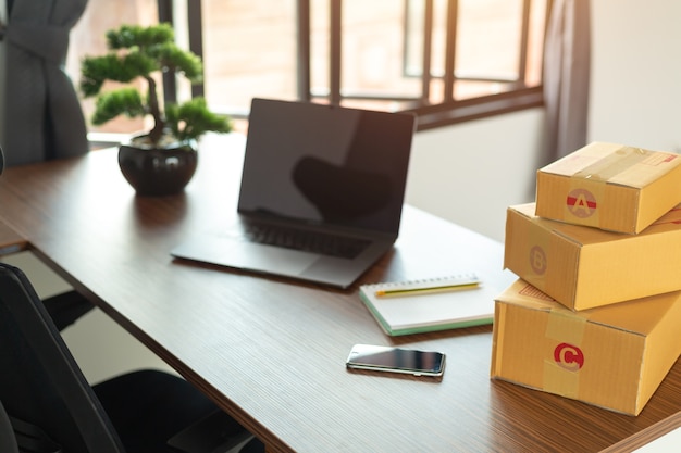 Laptop, carton box, parcel of goods to deliver to customers.