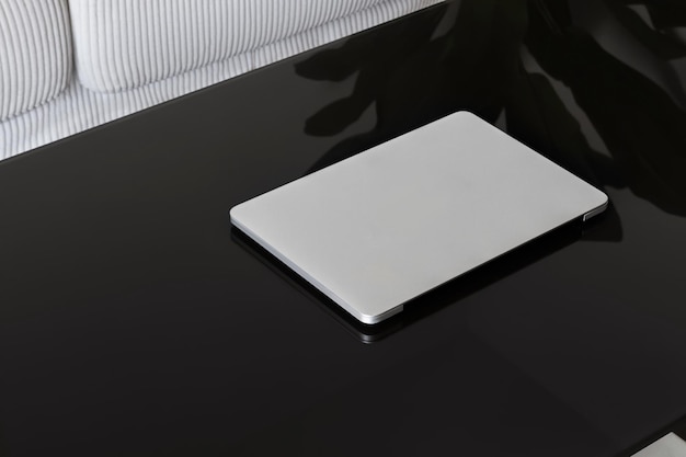 Laptop Closed Laptop on a black glass table against a white sofa