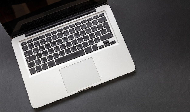 Laptop computer on black color background Open laptop keyboard metal silver top view Home office concept