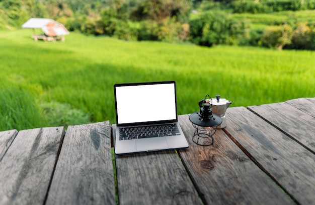 Laptop computer blank screen on a wooden terrace in the background of rice fieldsoutdoor laptop