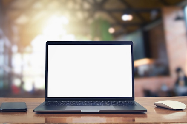 Laptop computer blank white screen and mobile on table in cafe background