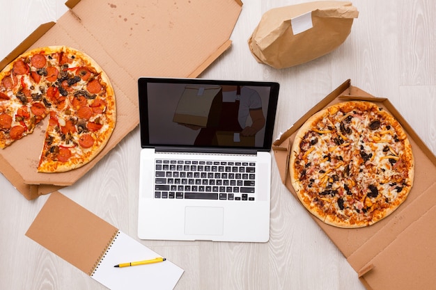 Photo laptop computer close-up with an appetizing pizza on white background