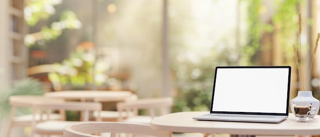 A laptop computer with a whitescreen mockup on a table in a beautiful comfortable coffee shop