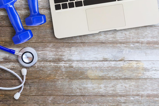 Laptop computerdumbbell with smart phone on wooden desk