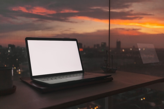 Laptop on the desk at the balcony with evening sunset city view