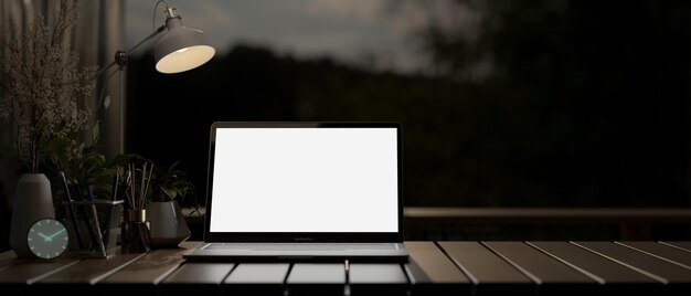 Photo a laptop on a desk in a dark room at night illuminated by a table lamp