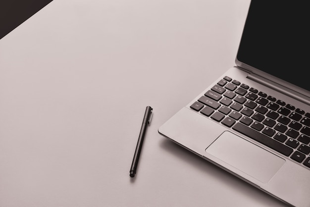 Laptop on the desk with the black pen placed on side