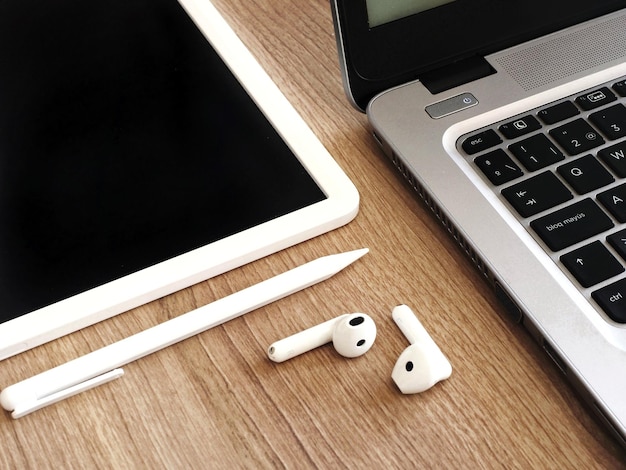 A laptop and earphones and a pen on a table ne