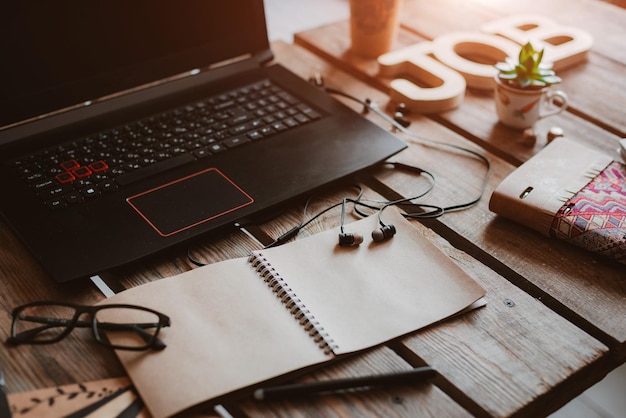 Laptop is a mix of office supplies and gadgets on the background wooden table