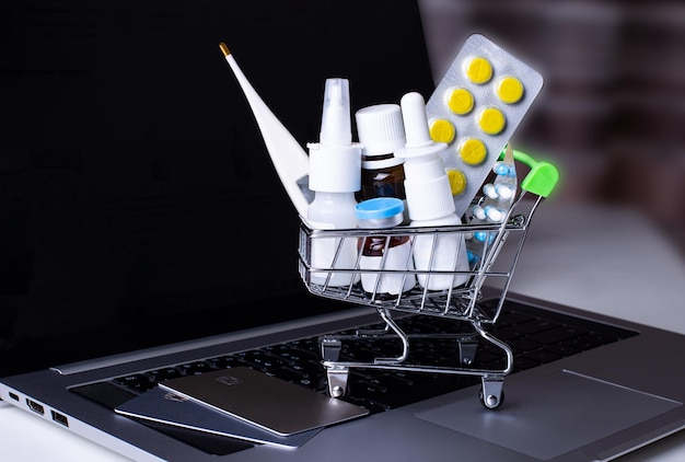 On the laptop is a shopping cart with medicines and credit cards Online shopping Medical concept Pharmacology