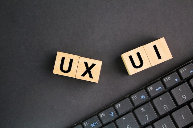 laptop keyboard and wooden blocks with the letters UX and UI User Interface and User Experience des