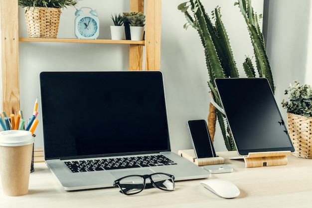 Laptop in a light room on working table with office supplies