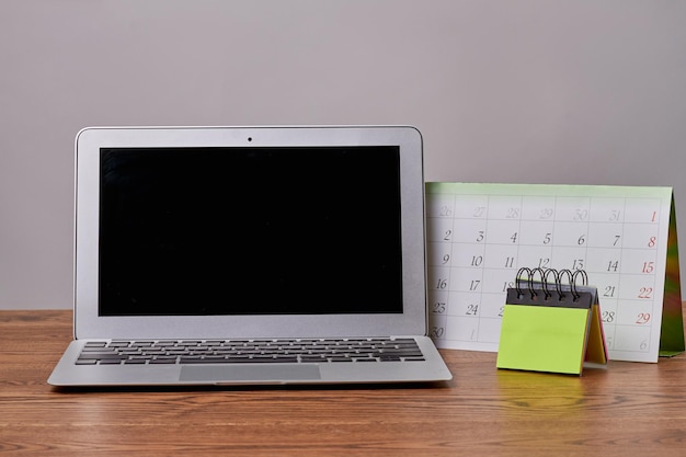 Laptop macbook with calendar and sticky notes on wooden desk notebook pc with black screen for copy