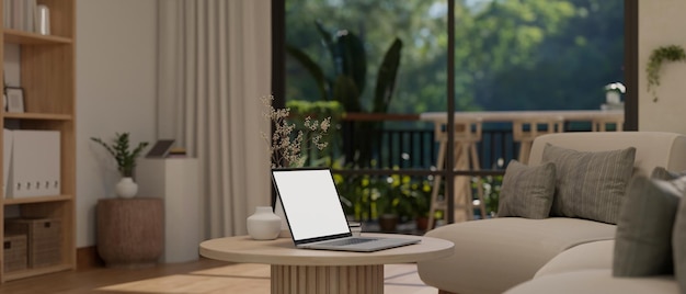 A laptop on a minimal round wooden coffee table in a modern and comfortable living room