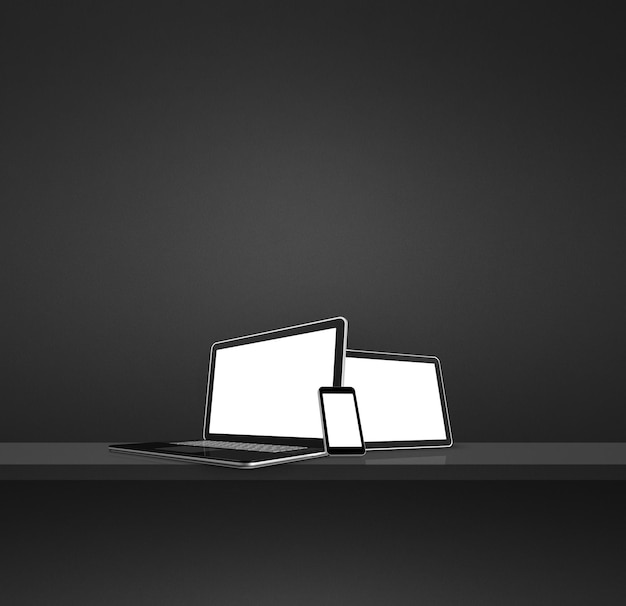 Laptop mobile phone and digital tablet pc on black wall shelf Square background