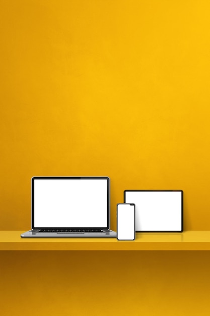 Laptop mobile phone and digital tablet pc on yellow wall shelf Vertical background