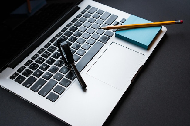 Laptop in modern workplace with office supplies magnifying glass yellow pencil and blue sticky notes