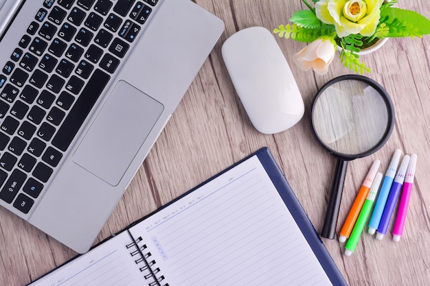 Laptop, notebook with magnifying glass on wooden table