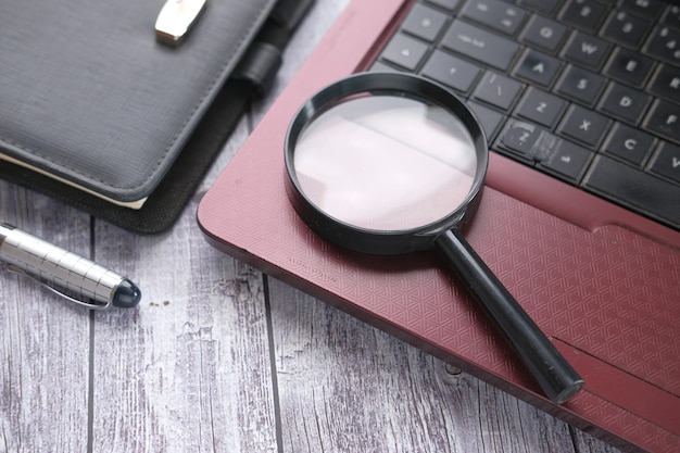 Laptop notepad and magnifying glass on table