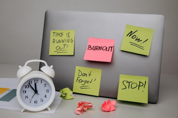 Laptop notes and clock on desk Overwhelmed with work