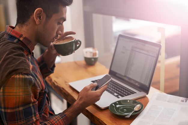 Photo laptop phone and man in coffee shop in morning typing for online message email and social media cafe restaurant and person on cellphone for communication networking and website for remote work