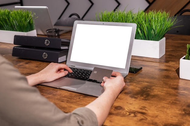 Laptop screen mockup and hands with bank credit card paying online making purchase with web site on blank computer display