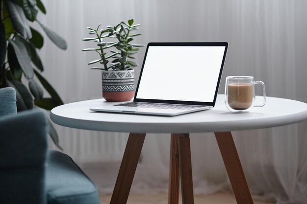 Laptop screen mockup on table with coffee cup and houseplant at home no people