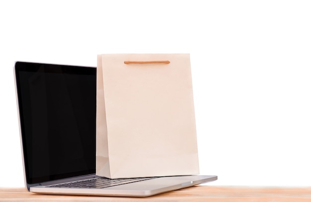 Laptop and shopping bag on a wooden surface. Isolation on a white background