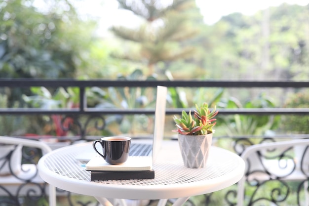 Photo laptop side view and coffee cup with notebooks on white table outdoor