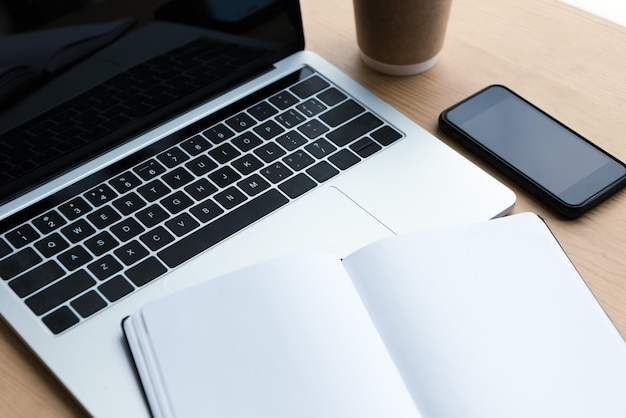 Laptop, smartphone and blank notebook on wooden table