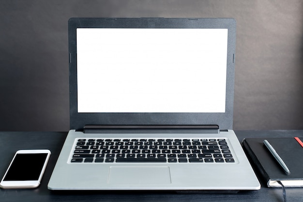 Laptop, smartphone, notebook, pen, on black wooden table with black background