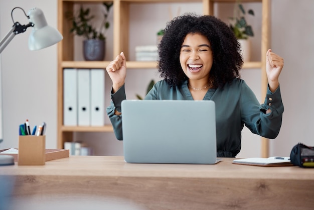 Laptop success and business woman in celebration at her desk in modern corporate office Happy celebrate and professional employee from Mexico with promotion successful project or goal achievement