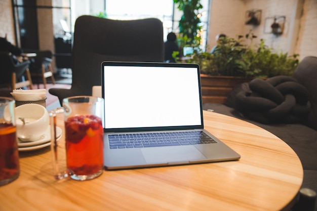 Laptop on the table in cafe with white screen. copy space