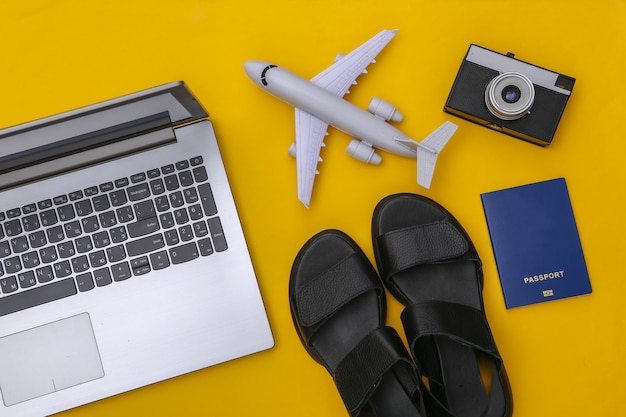 Laptop and travel accessories on yellow background. Top view. Flat lay