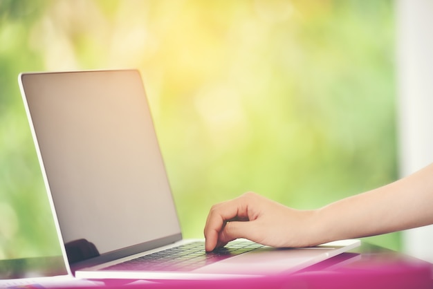 The laptop was used by a woman's hands to work with a garden background.