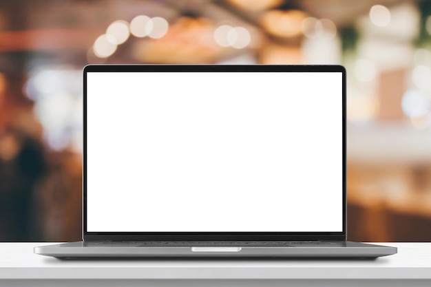 Laptop with blank screen on marble table with cafe coffee shop blur background