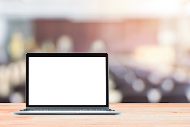 Laptop with blank screen placed on white wooden table in blurred people in Blurred conference room