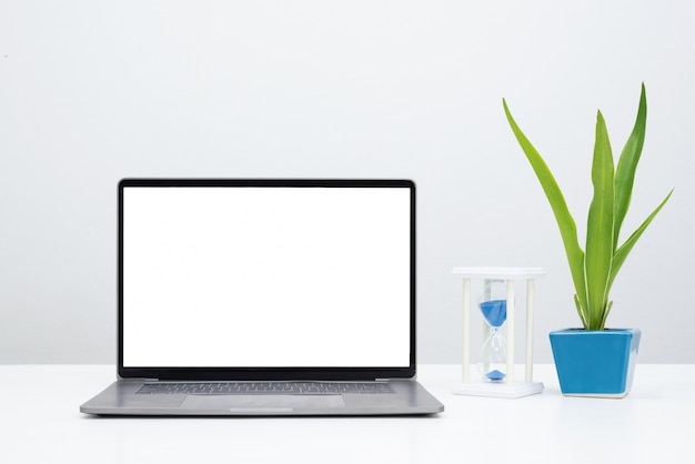 laptop with blank screen and plant with sandglass.