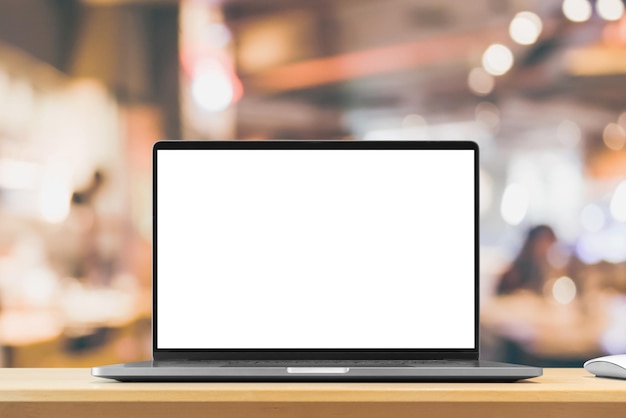 Laptop with blank screen on wood table with cafe coffee shop blur background