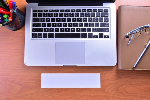 Laptop with blank white label and pen on wooden table