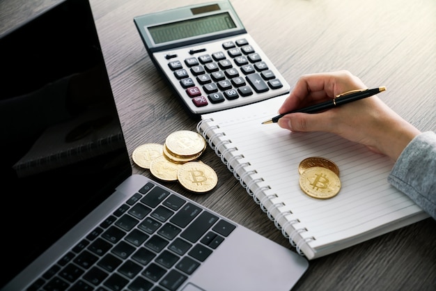 Laptop with calculator and golden bitcoin. Cryptocurrency investors concept.