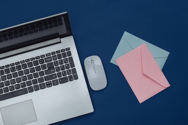 Laptop with pc mouse, envelopes on classic blue background. Color 2020. Top view.